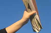 Hand mit Zeitungsrolle