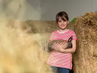 Kind mit Hase auf dem Arm vor Strohballen