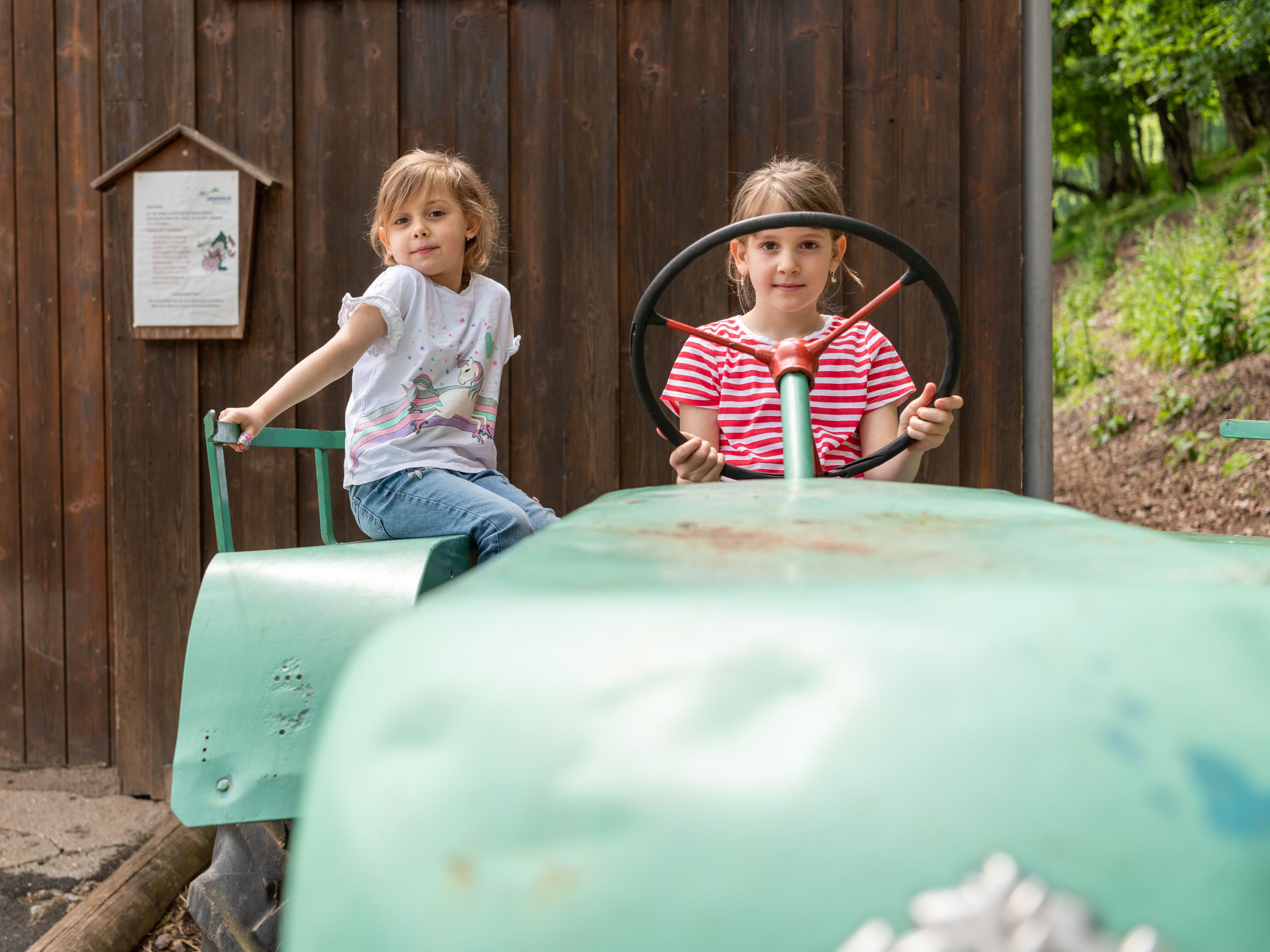 Zwei Mädchen auf dem Traktor vor Tannis Tierscheune