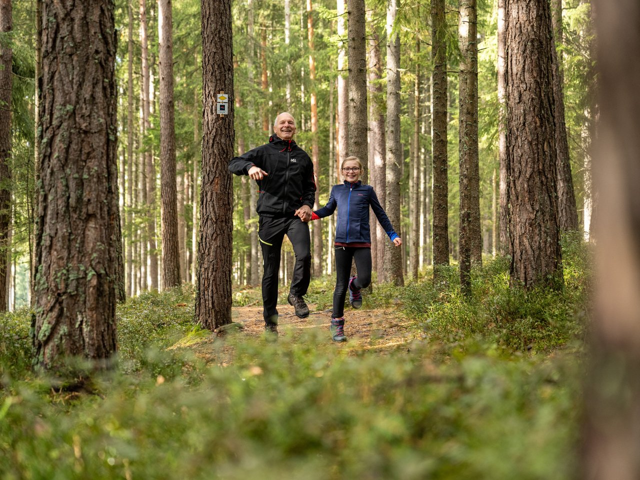 Opa und Enkelin hüpfen durch den Wald 
